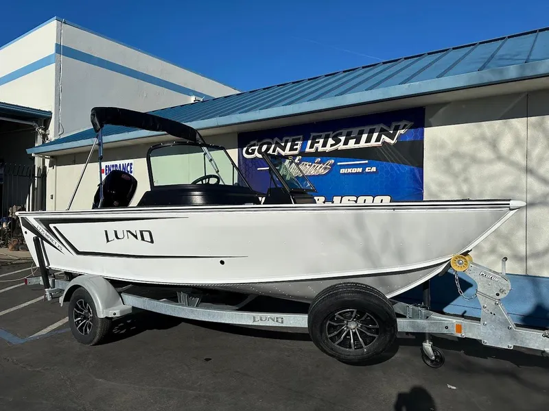 Slide: The Image of 2025 Lund 1775 Impact XS Sport boat on trailer, parked outside a building. - 1