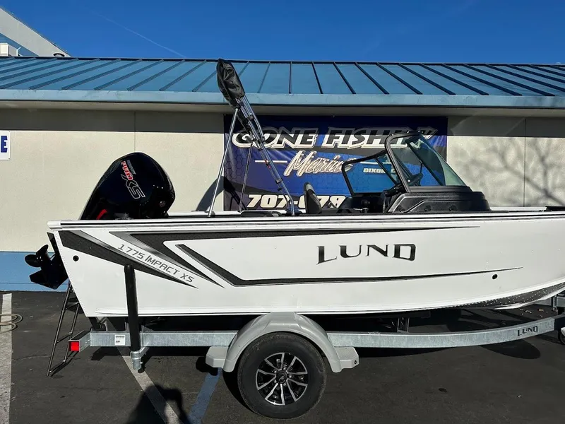 Slide: The Image of 2025 Lund 1775 Impact XS Sport boat on trailer, parked outside a building. - 5
