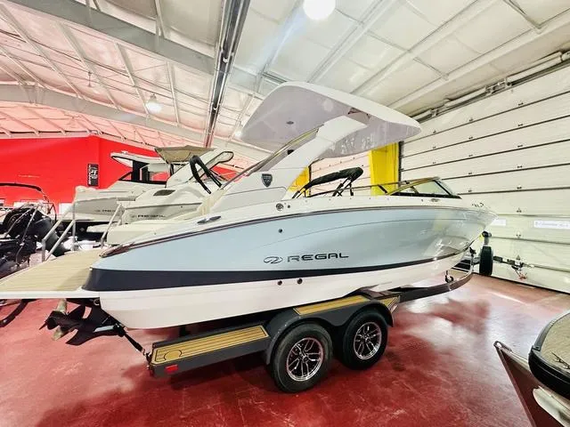 Slide: The Image of 2025 Regal LS6 boat on trailer in showroom, sleek design, white and gray exterior. - 7