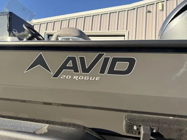 Slide: The Image of 2025 Avid 20 Rogue CC boat exterior with logo, parked near a building. - 3