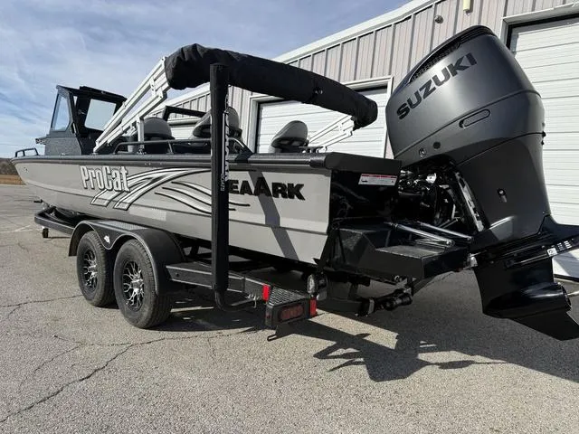Slide: The Image of 2025 SeaArk Pro Cat 240 boat with Suzuki engine, parked outside a garage. - 2