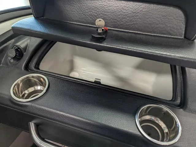 Slide: The Image of Crownline 240 SS 2023 boat dashboard with open glove compartment and cup holders. - 14