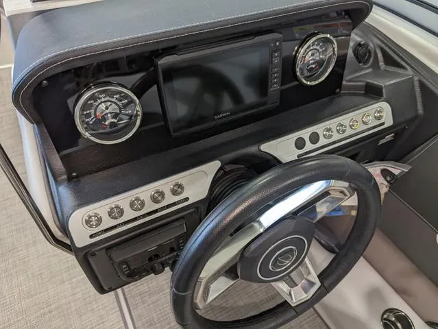 Slide: The Image of 2023 Crownline 240 SS dashboard with steering wheel, gauges, and navigation system. - 19