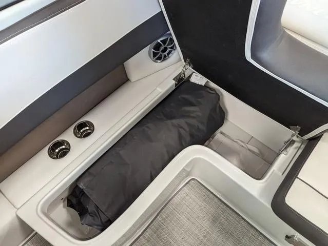 Slide: The Image of 2023 Crownline 240 SS boat interior storage compartment with black cover. - 21