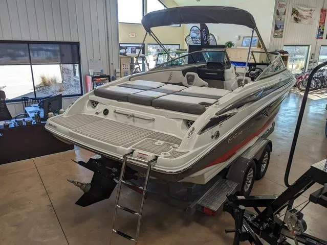 Slide: The Image of 2023 Crownline 240 SS boat in showroom, featuring spacious deck and seating. - 3