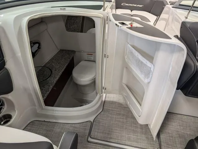 Slide: The Image of 2024 Crownline 280 SS boat interior with compact bathroom and seating area. - 17