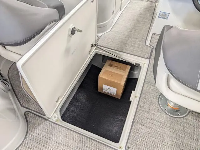 Slide: The Image of 2024 Crownline 280 SS boat storage compartment with a cardboard box inside. - 23