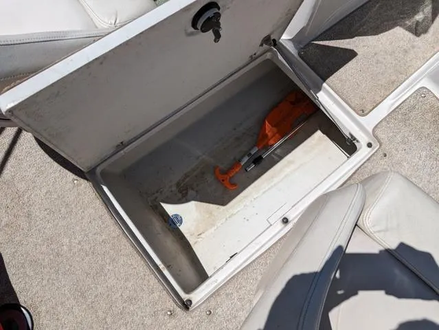 Slide: The Image of Open storage compartment in 2006 Crownline 220 LS boat, containing an orange tool. - 19