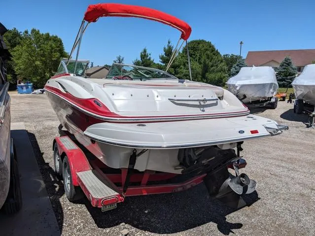Slide: The Image of 2006 Crownline 220 LS boat with red accents on a trailer, parked outdoors. - 23