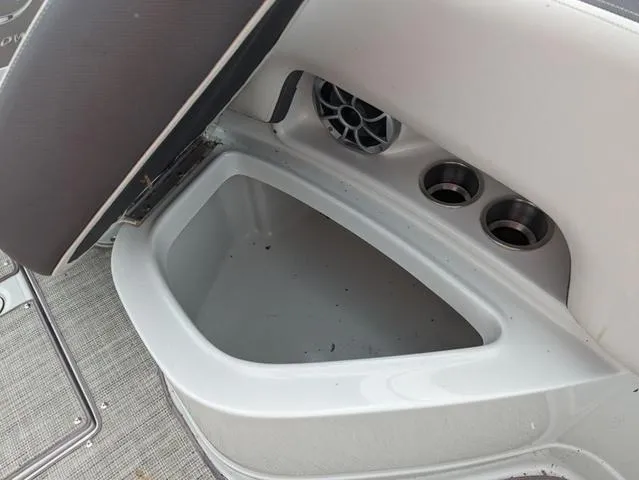Slide: The Image of 2022 Crownline E235 XS boat storage compartment with cup holders and speaker. - 16