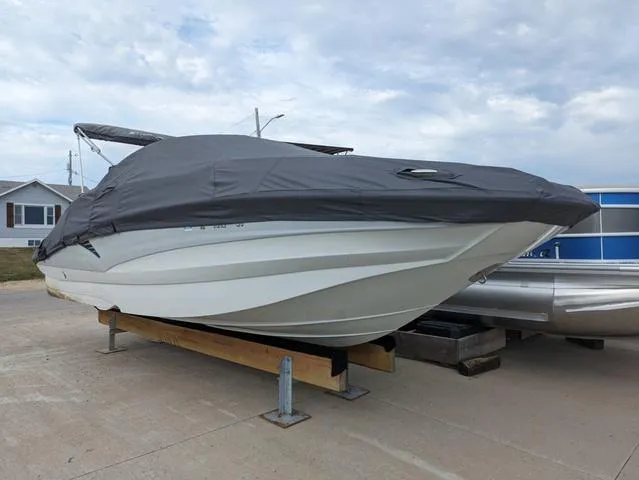 Slide: The Image of 2022 Crownline E235 XS boat with cover on a trailer, parked outdoors. - 17