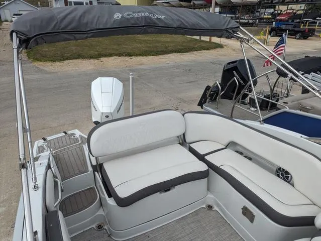 Slide: The Image of 2022 Crownline E235 XS boat with spacious seating and canopy in a marina setting. - 8