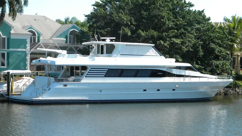 Slide: The Image of 1999 Tarrab Motoryacht docked by waterfront homes, surrounded by lush greenery. - 1