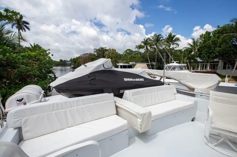 Slide: The Image of Tarrab Motoryacht 1999 with white seating and covered Sea-Doo, docked by lush greenery. - 28