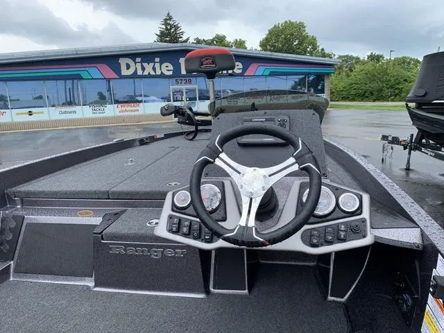 Slide: The Image of 2025 Ranger Z185 boat dashboard with steering wheel, parked outside Dixie Marine store. - 3