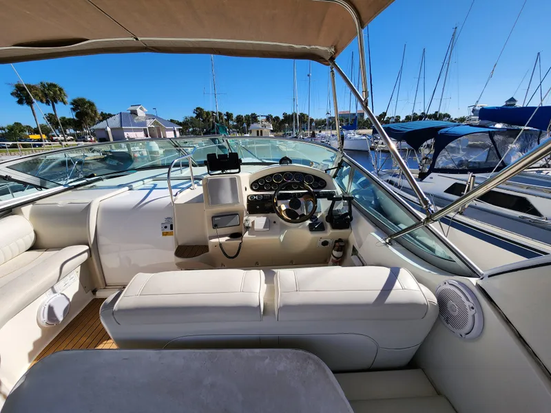Slide: The Image of 1999 Cruisers Yachts 3375 Esprit cockpit with helm, marina view, and clear blue sky. - 12