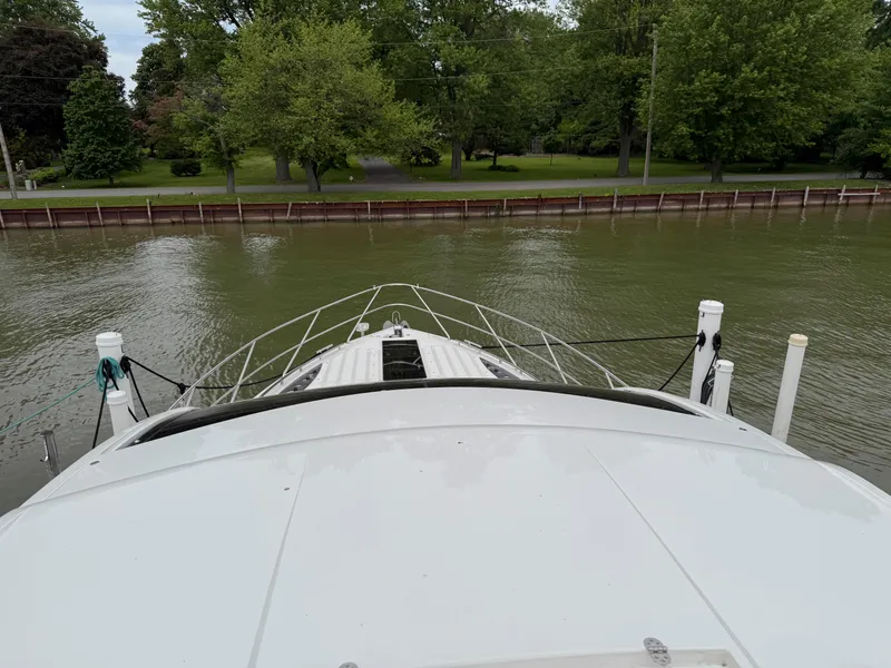 Slide: The Image of Bow view of 2018 Galeon 560 Sky yacht docked by a tree-lined shore. - 13