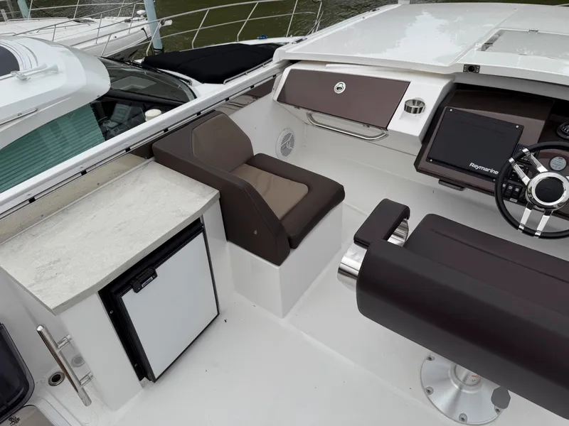 Slide: The Image of 2018 Galeon 560 Sky yacht cockpit with seating, steering wheel, and mini fridge. - 15