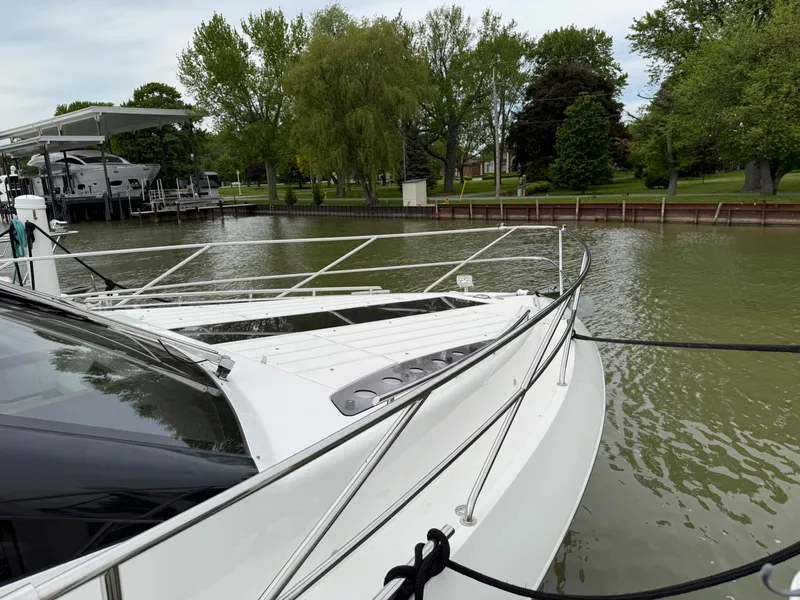 Slide: The Image of 2018 Galeon 560 Sky yacht docked by a serene, tree-lined waterfront. - 7