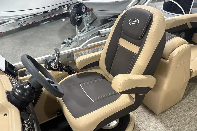 Slide: The Image of 2025 Barletta C22QC boat interior with beige and brown captain's chair and steering wheel. - 25