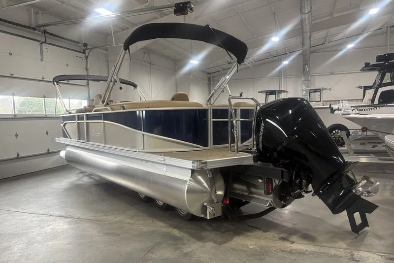 Slide: The Image of 2025 Barletta C22QC pontoon boat in a showroom, featuring a sleek design and powerful outboard motor. - 38