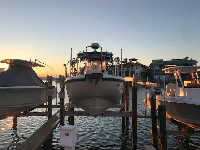 Slide: The Image of 1998 Boston Whaler 260 Outrage docked at sunset, surrounded by water and boats. - 2