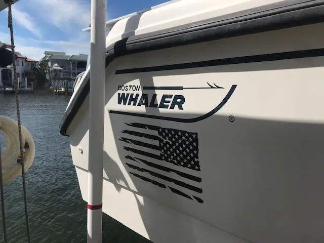 Slide: The Image of 1998 Boston Whaler 260 Outrage boat with American flag decal, docked by waterfront homes. - 35