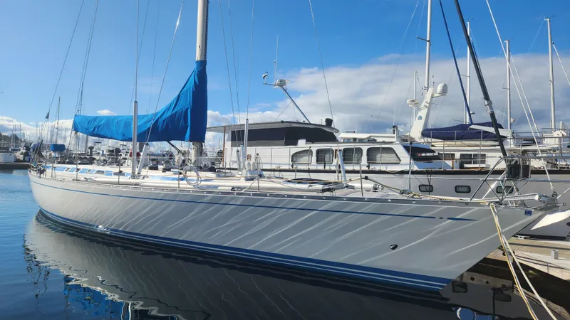 Slide: The Image of 1983 Nautor Swan 651 yacht docked in marina, blue sail cover, clear sky. - 1
