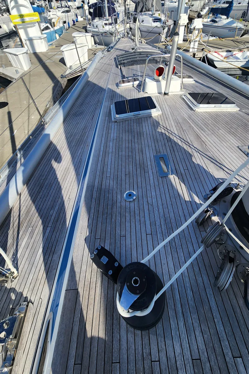Slide: The Image of Deck of 1983 Nautor Swan 651 yacht in marina, showcasing teak wood and rigging. - 12