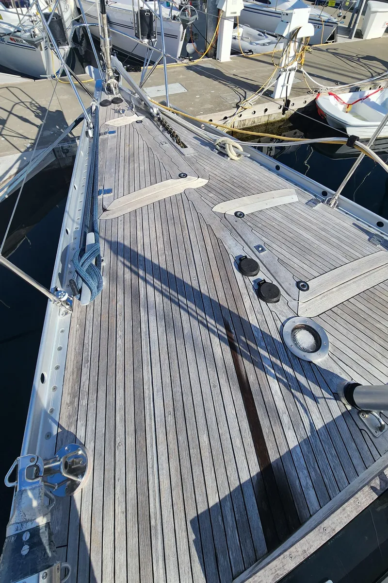 Slide: The Image of 1983 Nautor Swan 651 yacht deck with wooden finish, docked at a marina. - 14