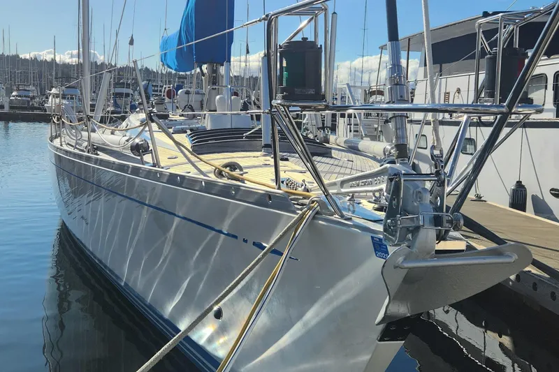 Slide: The Image of 1983 Nautor Swan 651 yacht docked in a marina, reflecting sunlight on the water. - 2