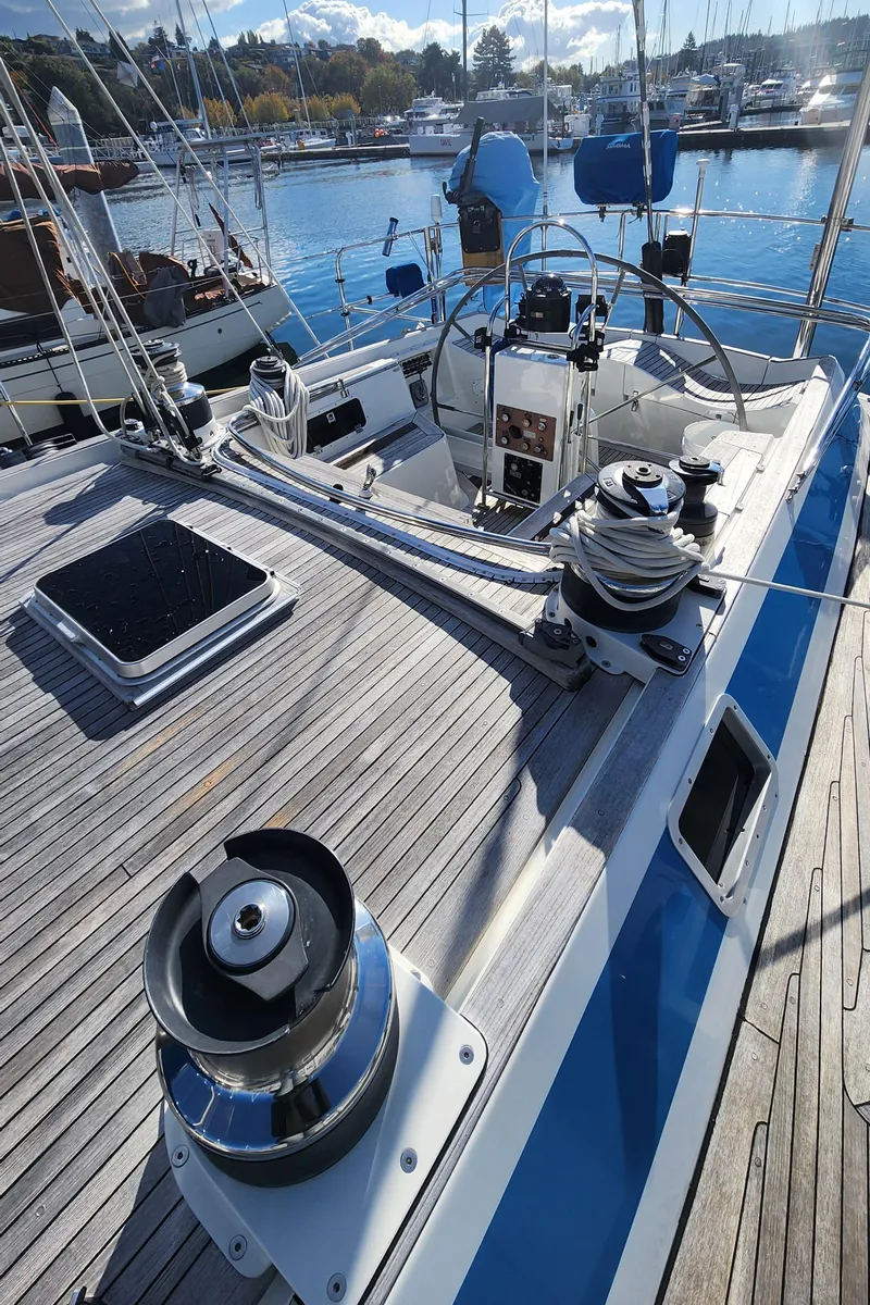Slide: The Image of 1983 Nautor Swan 651 sailboat deck with winches and steering wheel in a marina. - 25