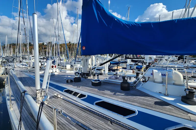 Slide: The Image of Sailboat Nautor Swan 651, 1983 model, docked in a marina with blue sail cover. - 6