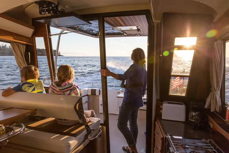 Slide: The Image of Interior view of 2025 Ranger Tugs R-29 CB boat with passengers enjoying sunset. - 5