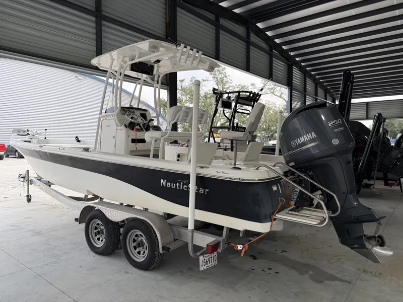 Slide: The Image of 2014 NauticStar NauticBay 244 XTS boat with Yamaha 250 engine on trailer in covered storage. - 2