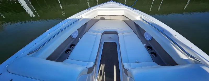 Slide: The Image of 2006 Cobalt 240 boat interior with white seating and cup holders, docked on calm water. - 11