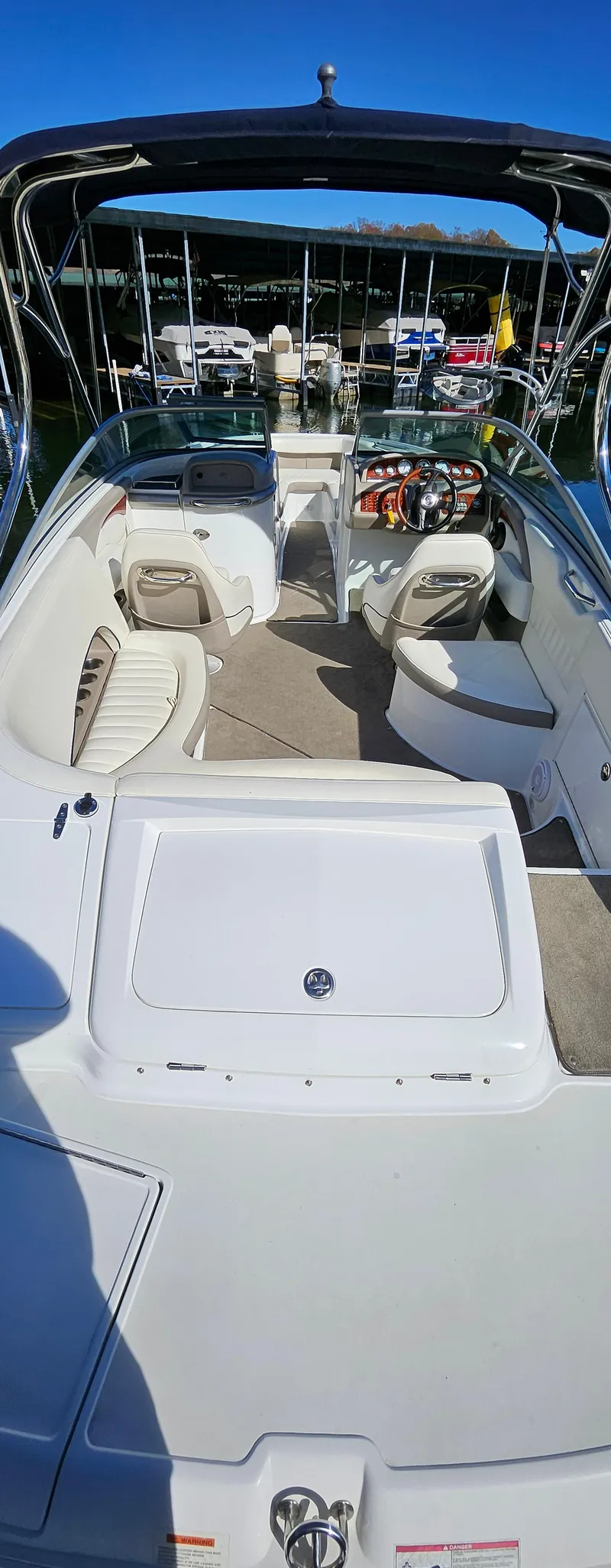 Slide: The Image of 2006 Cobalt 240 boat interior with seating and steering wheel, docked under clear blue sky. - 6