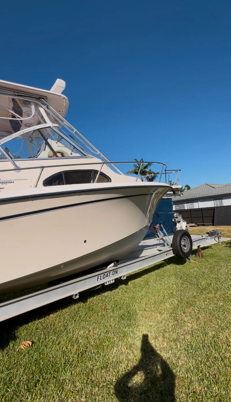 Slide: The Image of 2006 Grady-White 282 Sailfish boat on trailer, parked on grass under clear blue sky. - 21