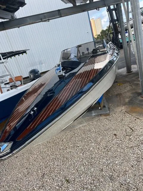 Slide: The Image of 1977 Riva 310 boat with sleek wooden deck, docked on gravel. - 15