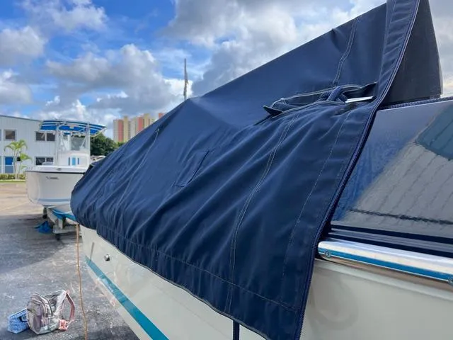 Slide: The Image of 1977 Riva 310 boat with blue cover, parked outdoors under cloudy sky. - 24