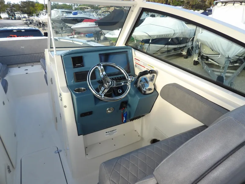 Slide: The Image of 2022 Stingray 269 DC boat cockpit with steering wheel and seating. - 25