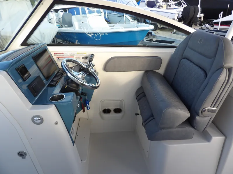Slide: The Image of 2022 Stingray 269 DC boat interior with steering wheel and cushioned seating. - 26