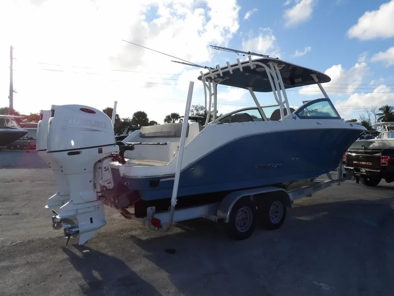 Slide: The Image of 2022 Stingray 269 DC boat on trailer, parked outdoors under a partly cloudy sky. - 6