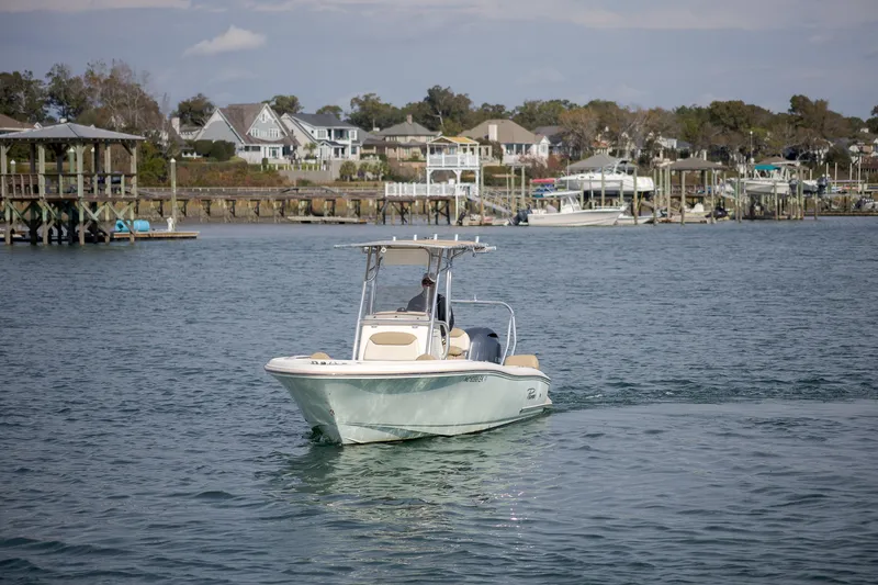 Slide: The Image of 2019 Pioneer 202 Sportfish boat cruising near coastal homes and docks. - 6