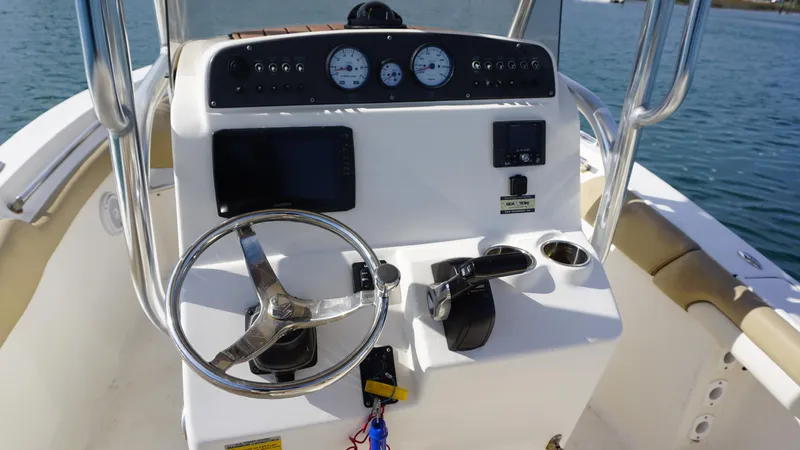 Slide: The Image of 2019 Pioneer 202 Sportfish boat console with steering wheel and gauges on water. - 8