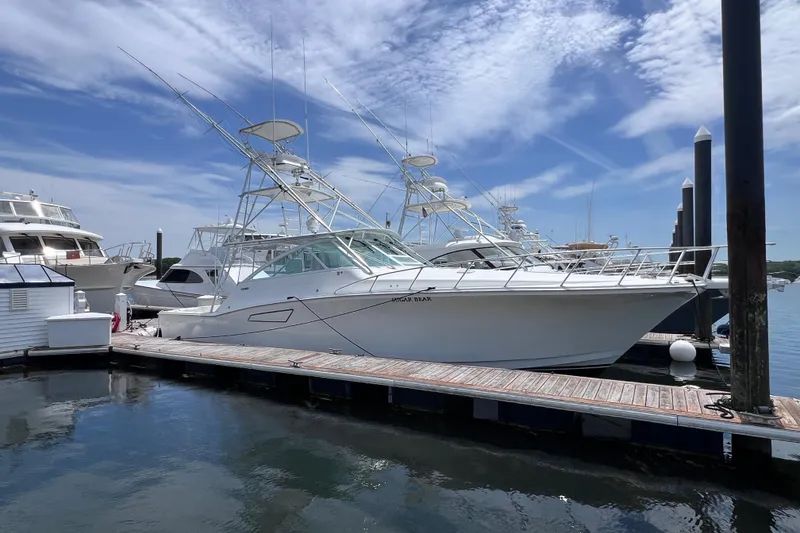 The Image of 2001 Cabo 45 Express yacht docked at marina under blue sky. - 0