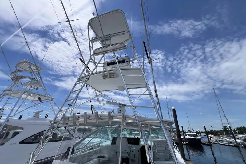 Slide: The Image of 2001 Cabo 45 Express yacht with tower against a blue sky at marina. - 16