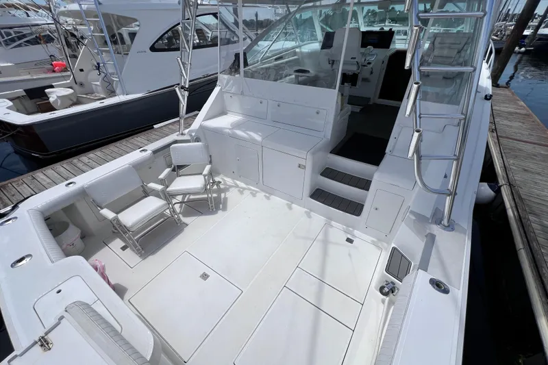 Slide: The Image of 2001 Cabo 45 Express yacht with spacious deck, seating, and ladder at marina. - 22