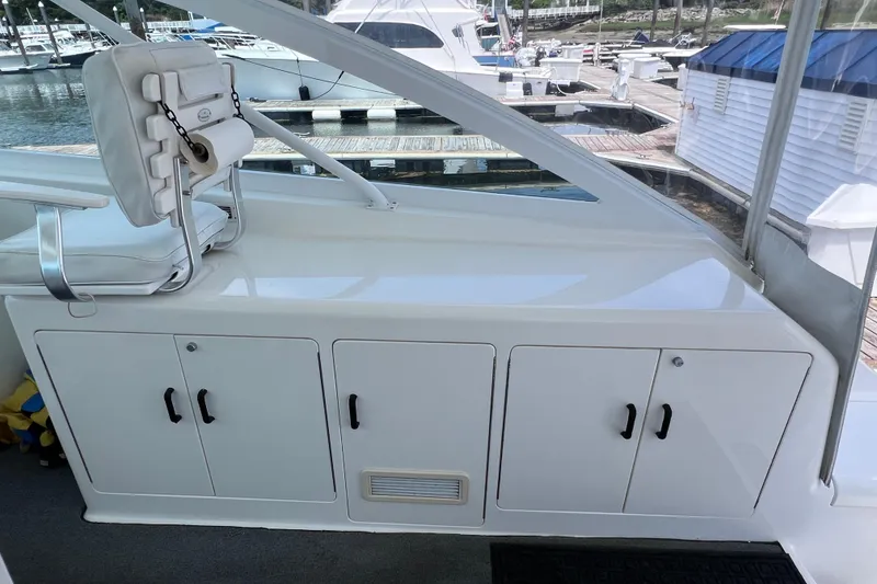 Slide: The Image of 2001 Cabo 45 Express boat interior with white seating and storage cabinets at marina. - 32
