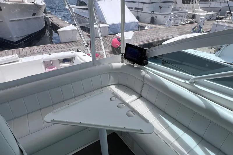Slide: The Image of 2001 Cabo 45 Express yacht interior with white seating and triangular table at marina. - 33